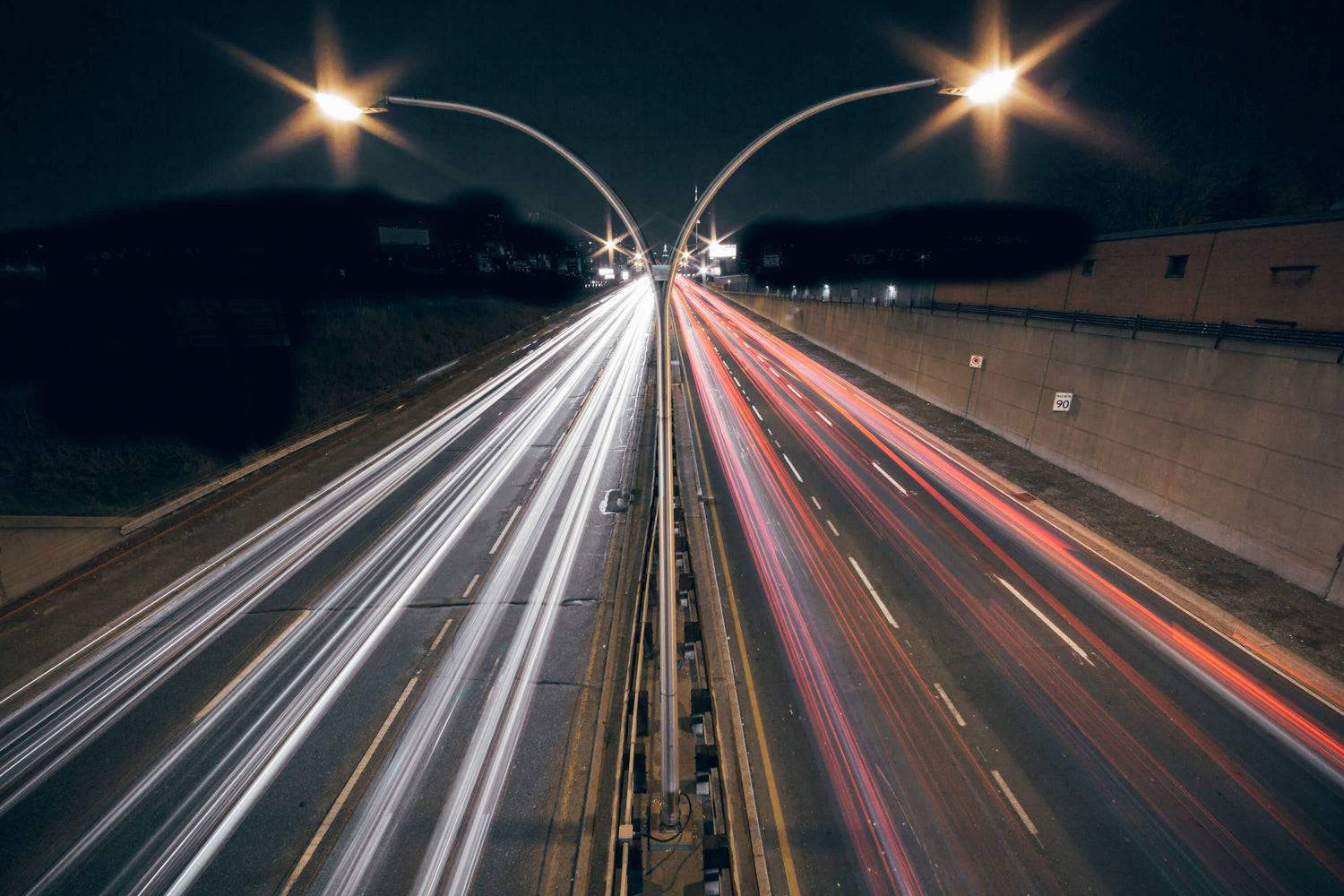 Two-way highway traffic at night, with fast-moving vehicles appearing as a blur.