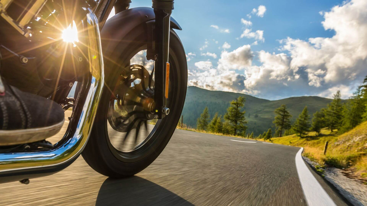 View of a motorcycle wheel traveling down an open road.